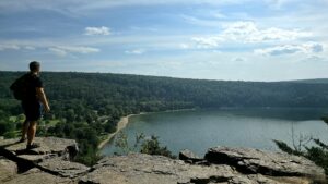 Hiker overlooking a lake and forest from a rocky overlook.
